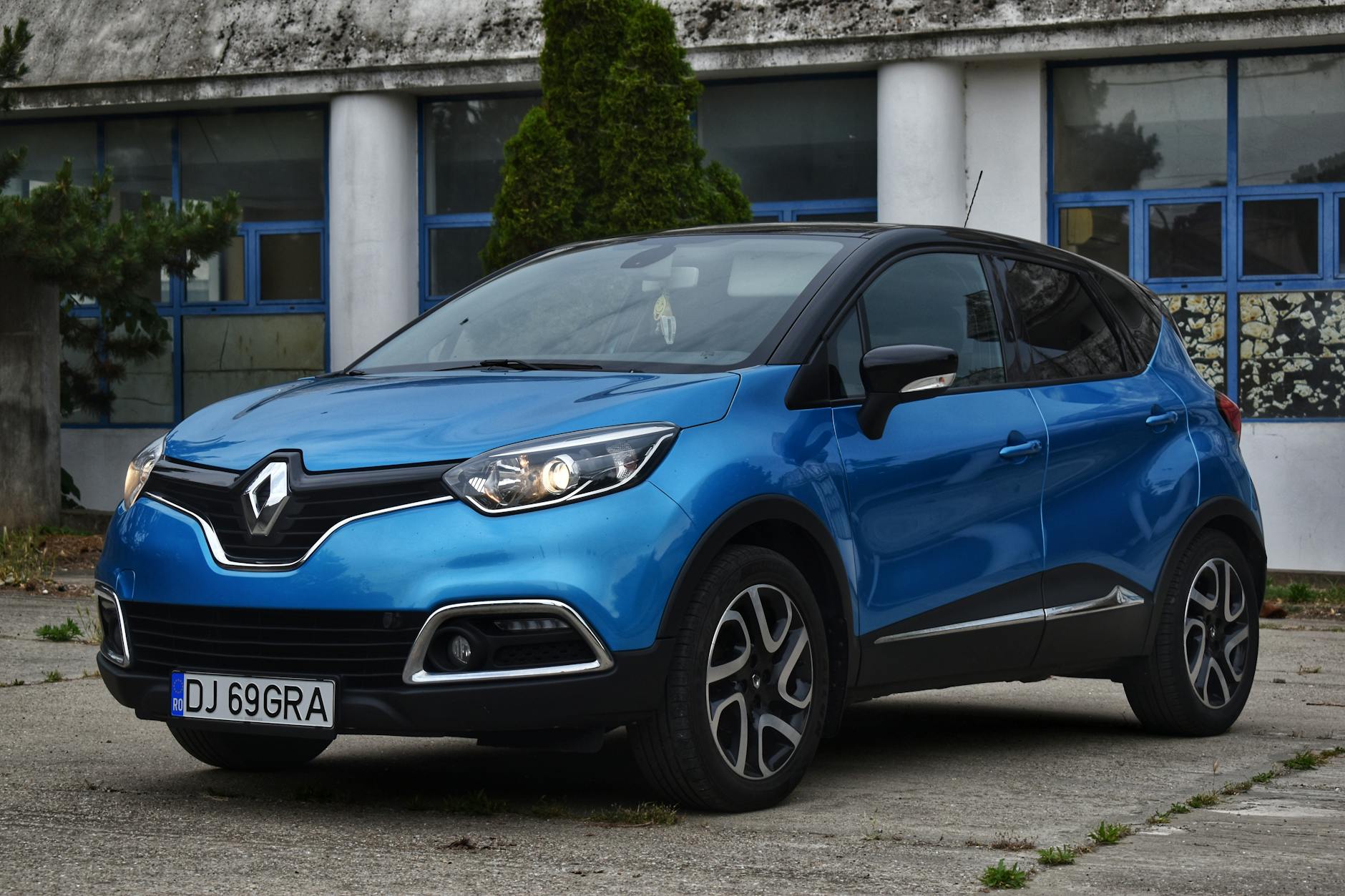 Niebieski Renault z rumuńską rejestracją zaparkowany przy budynku