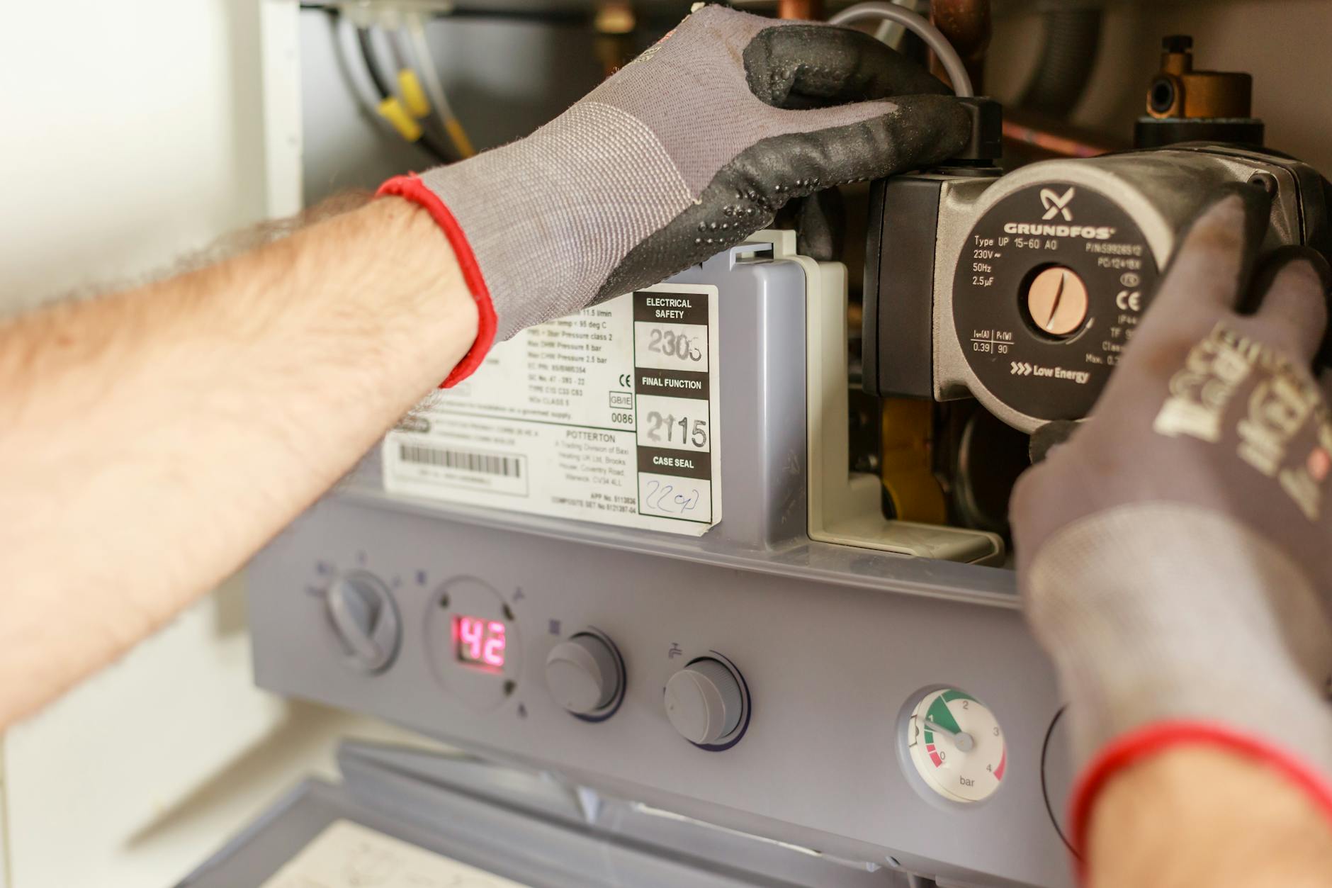 Ręce regulujące kocioł z precyzyjną aparaturą w instalacji wodnej