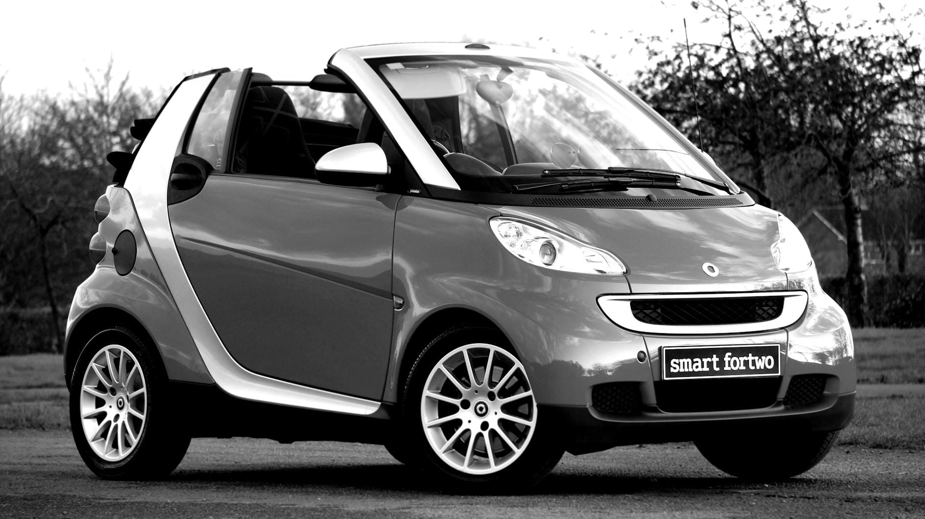 Czarno-białe zdjęcie klasycznego kabrioletu Smart Fortwo na parkingu