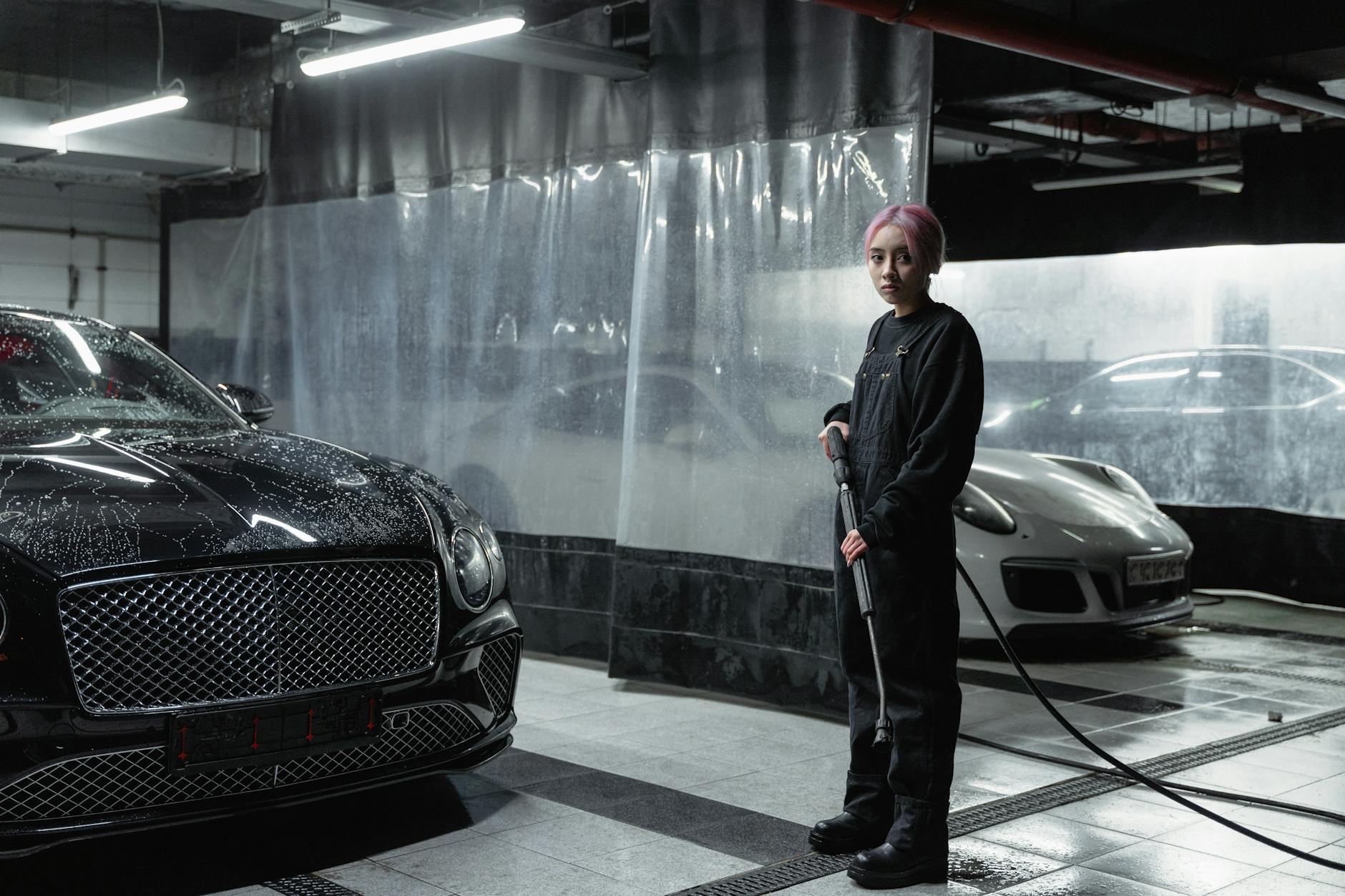 Kobieta myje luksusowy samochód myjką ciśnieniową w serwisie Aston Martin