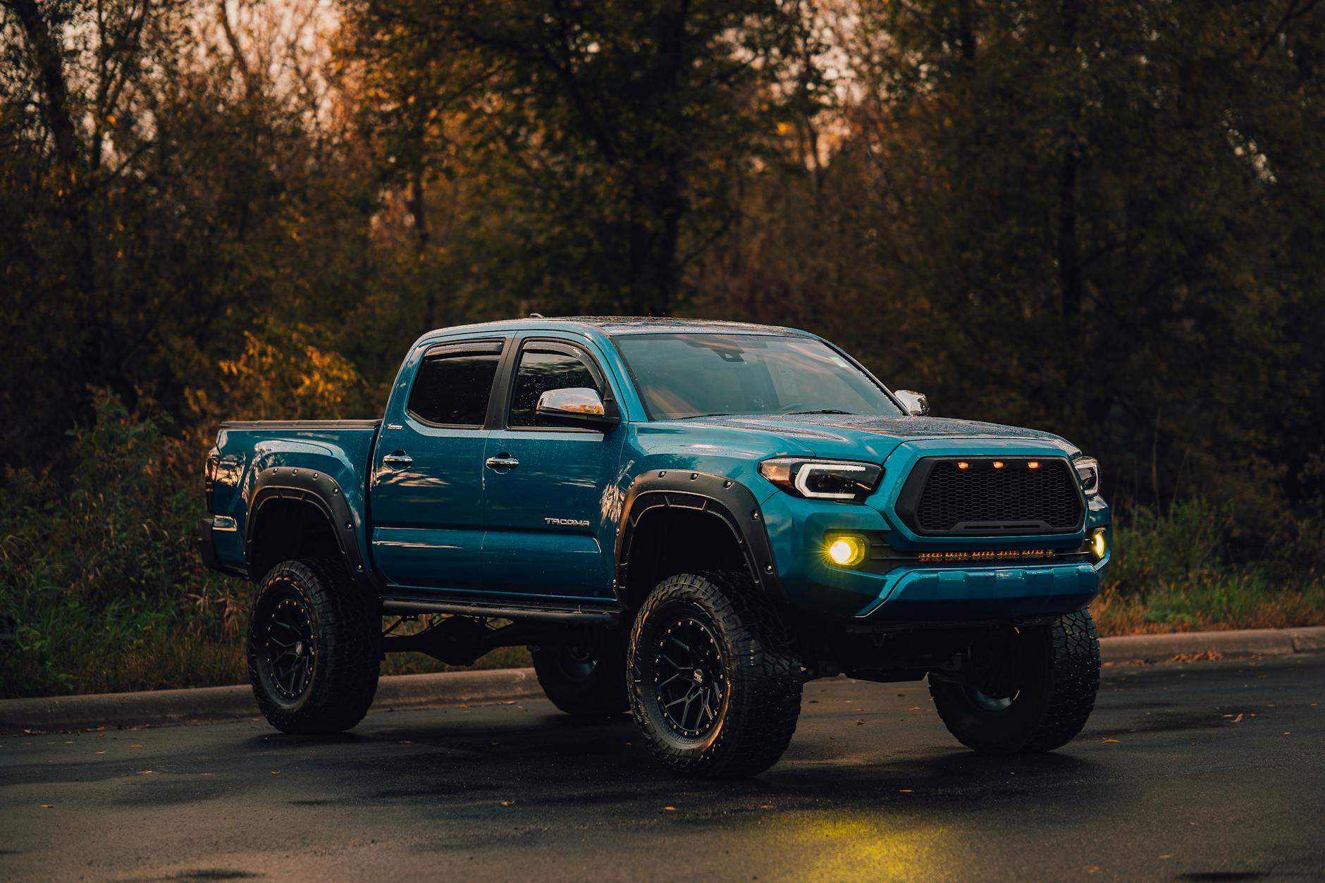 Niebieski Ford Ranger na mokrej drodze w lesie
