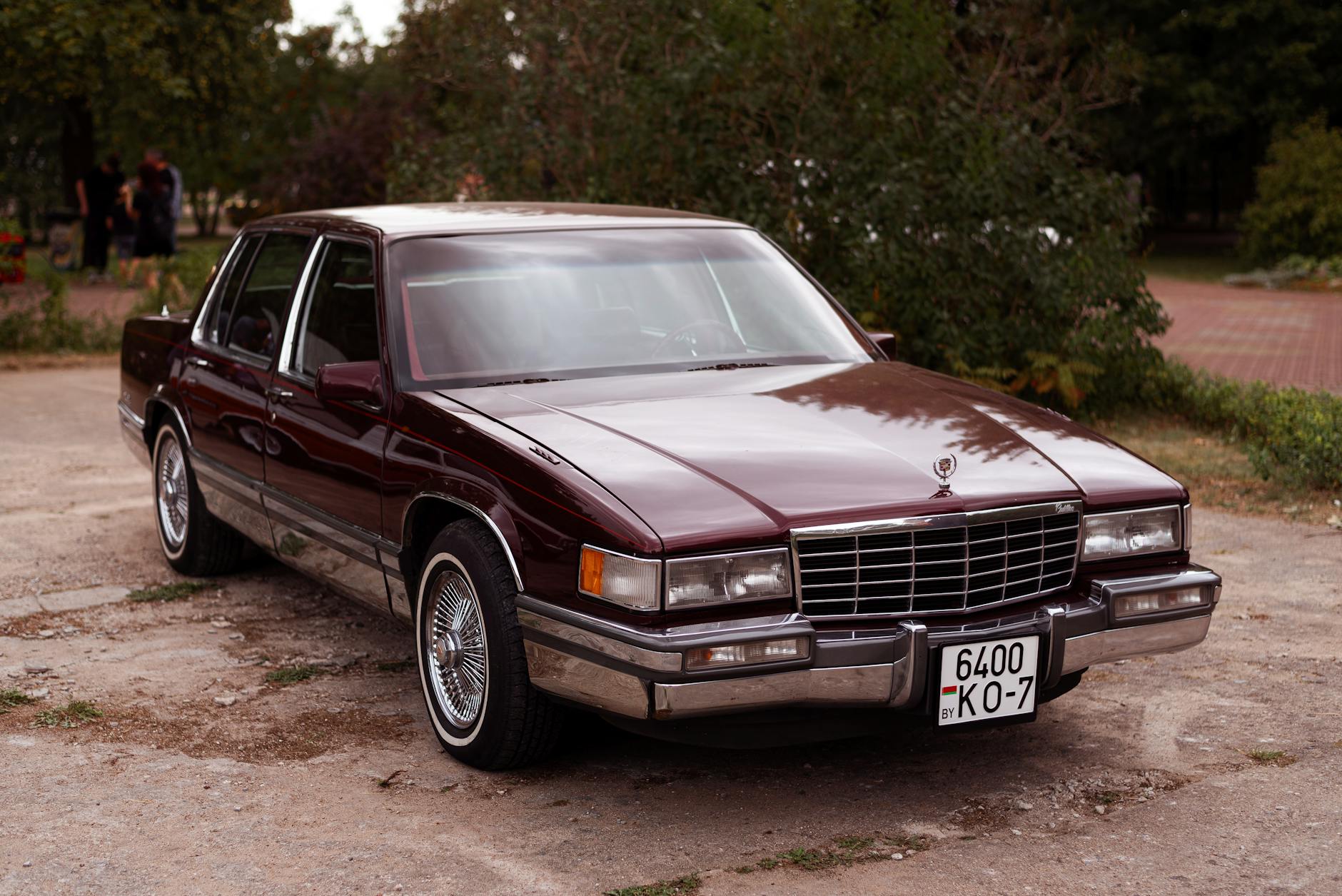 Srebrny Cadillac DeVille zaparkowany na słońcu, podkreślający luksus