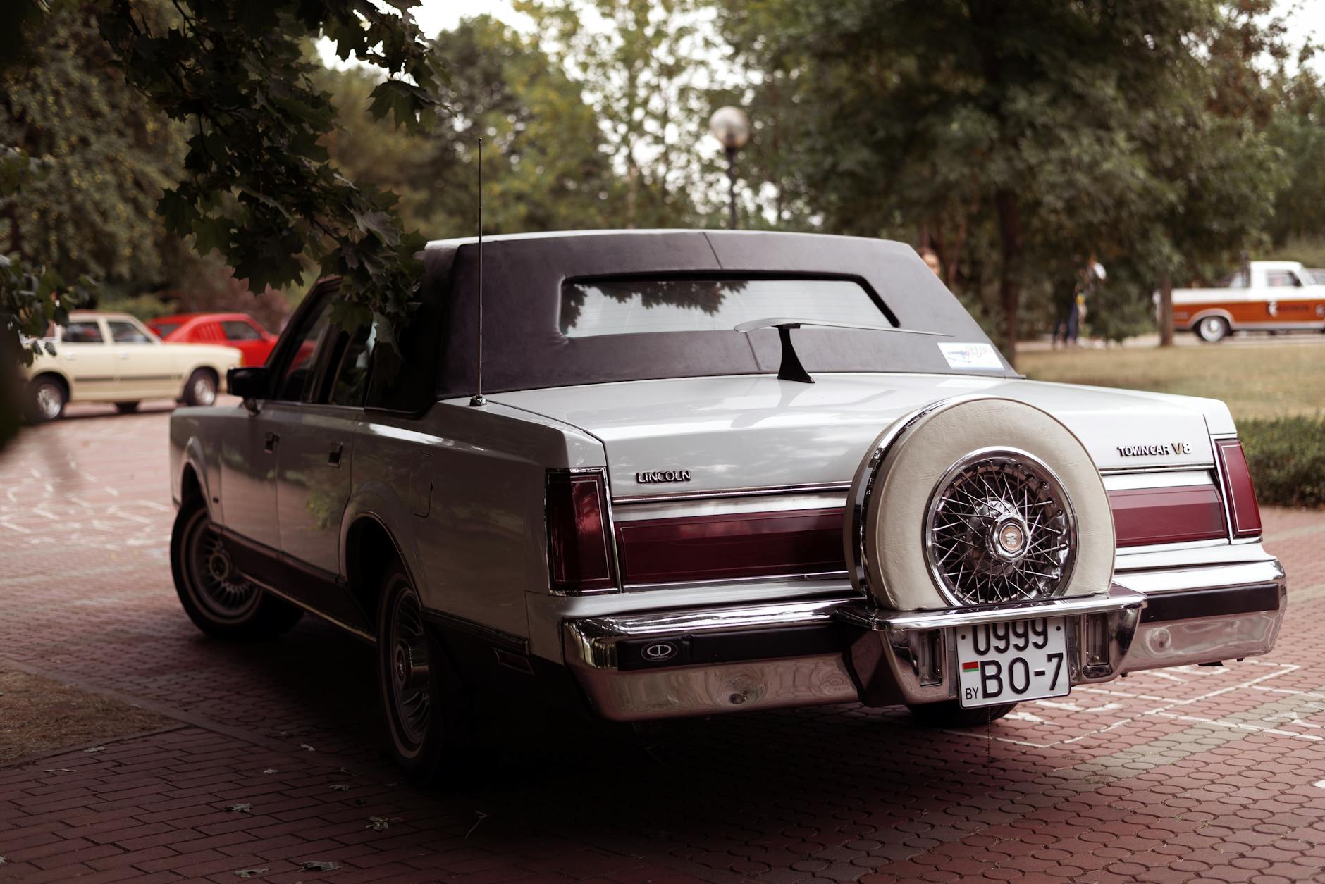 Tył klasycznego sedana Lincoln Town Car na podjeździe z innymi autami