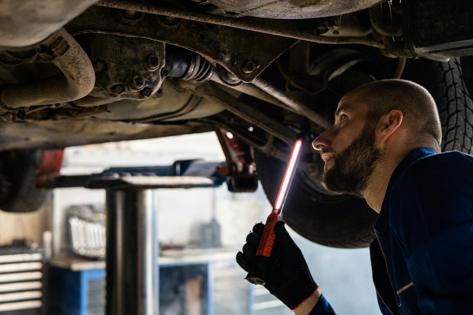 Mechanik z latarką sprawdza podwozie używanego Geely w warsztacie
