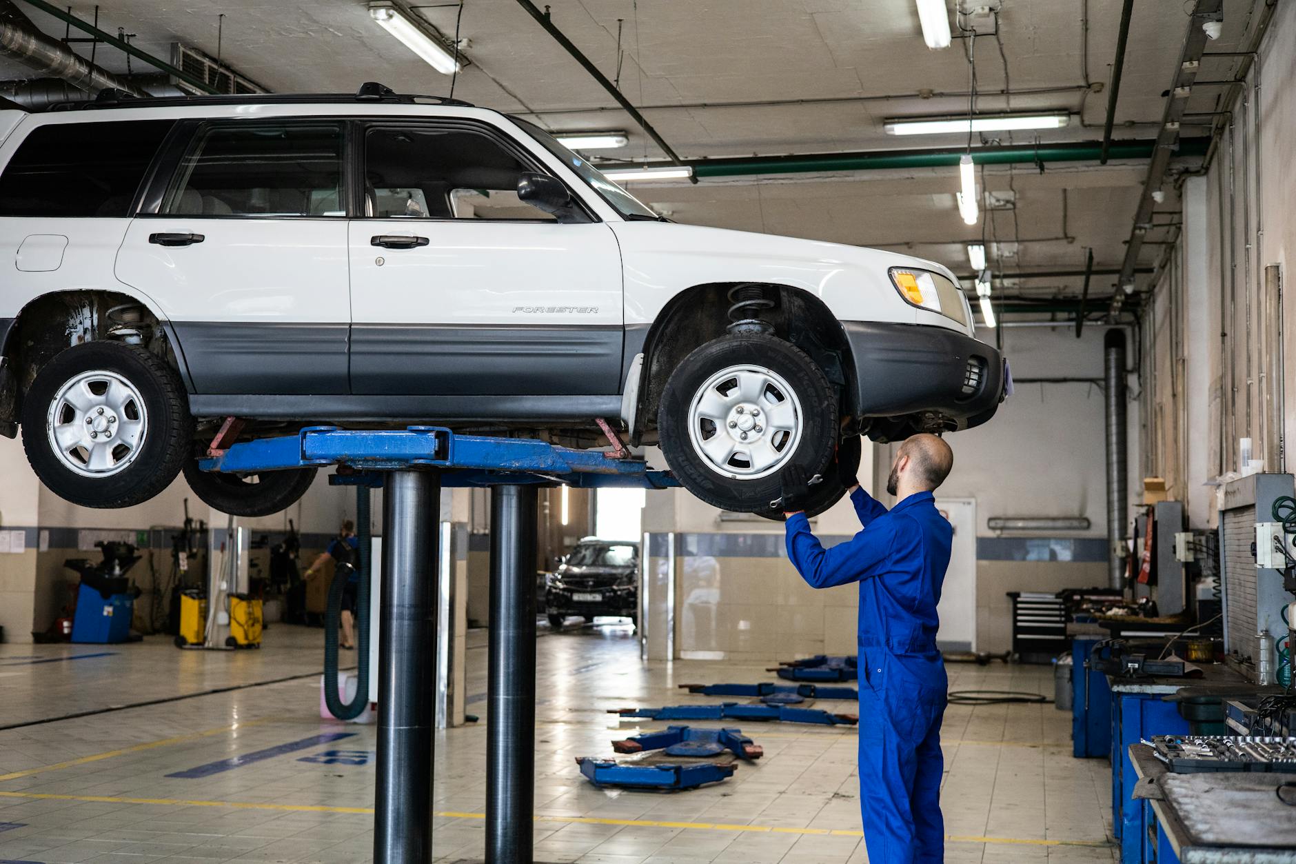 Mechanik ogląda podwozie białego SUV-a Mitsubishi w warsztacie samochodowym