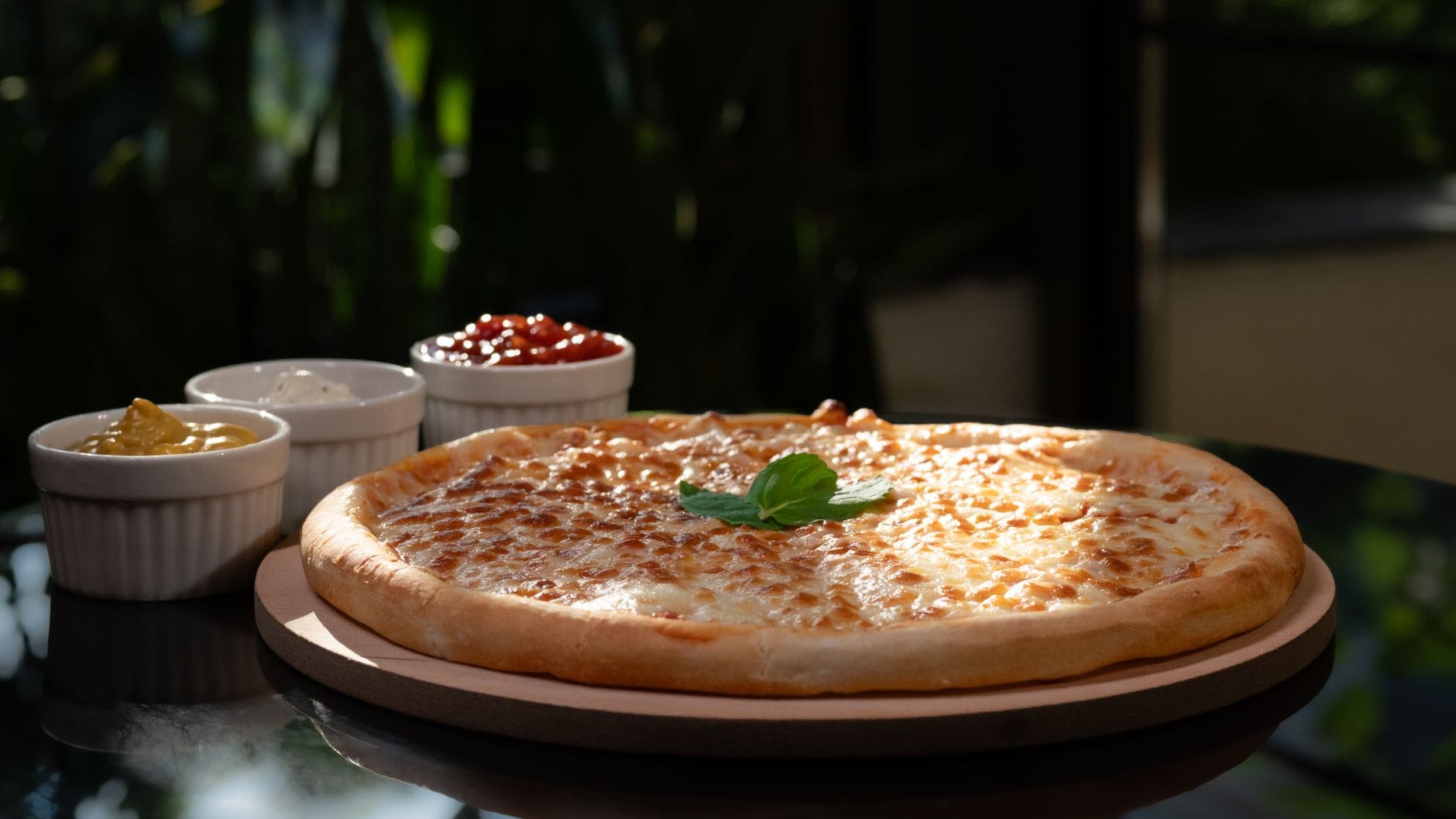Pizza serowa z miseczkami sosu czosnkowego w naturalnym świetle