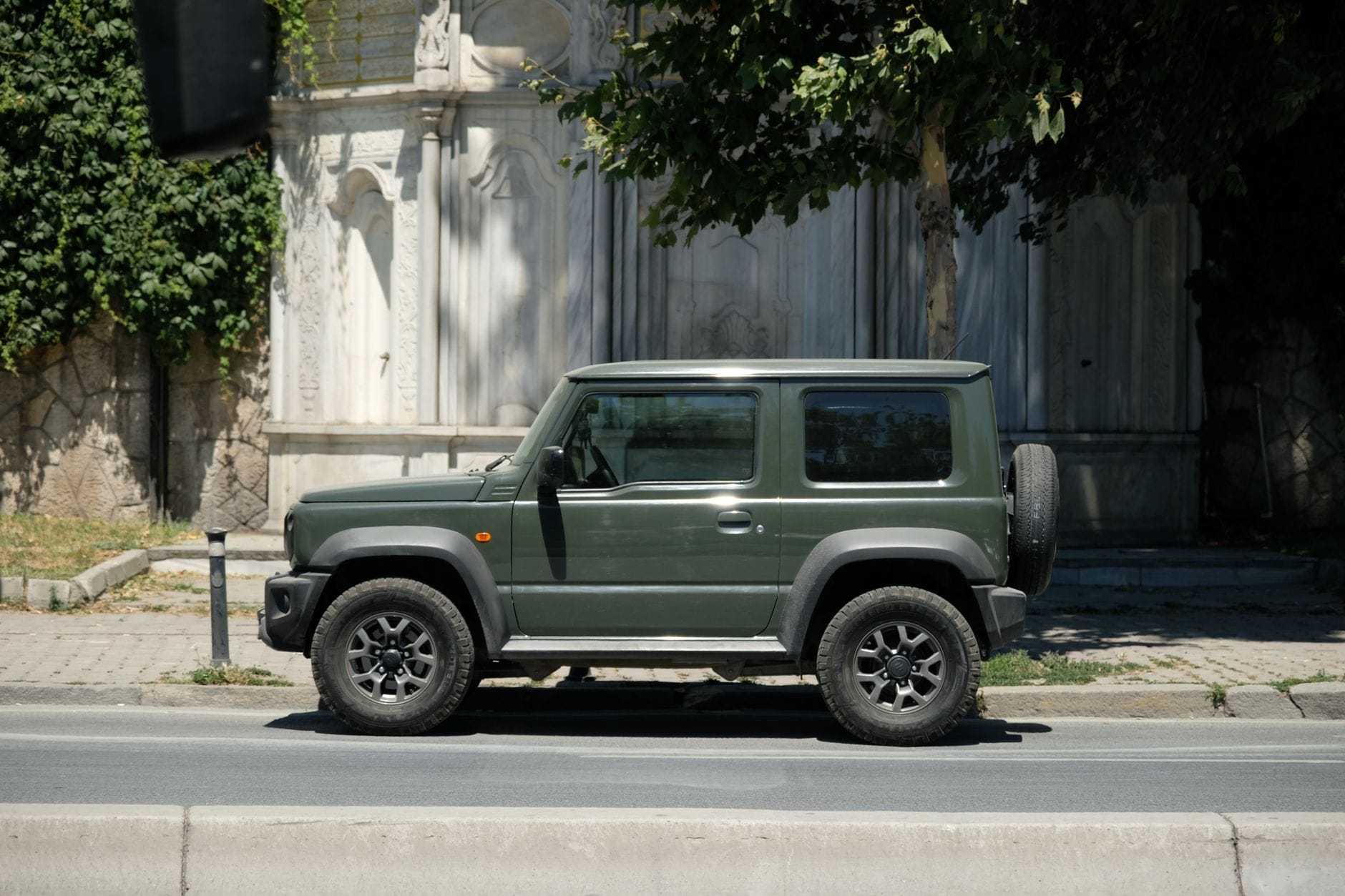 Zielone Suzuki 4x4 zaparkowane przy słonecznej miejskiej ulicy