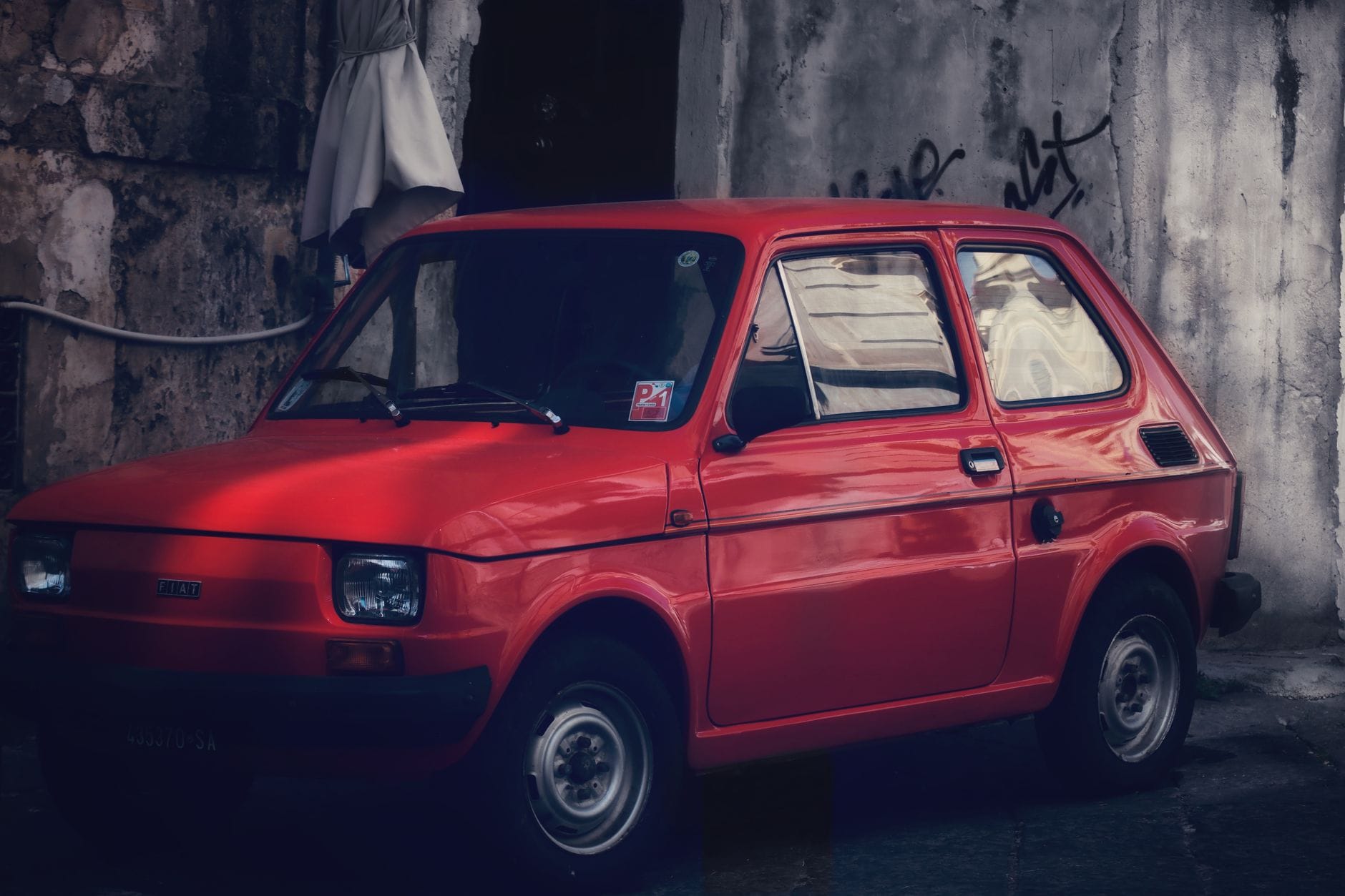 Czerwony Fiat 126p zaparkowany w mieście, klasyczny polski maluch