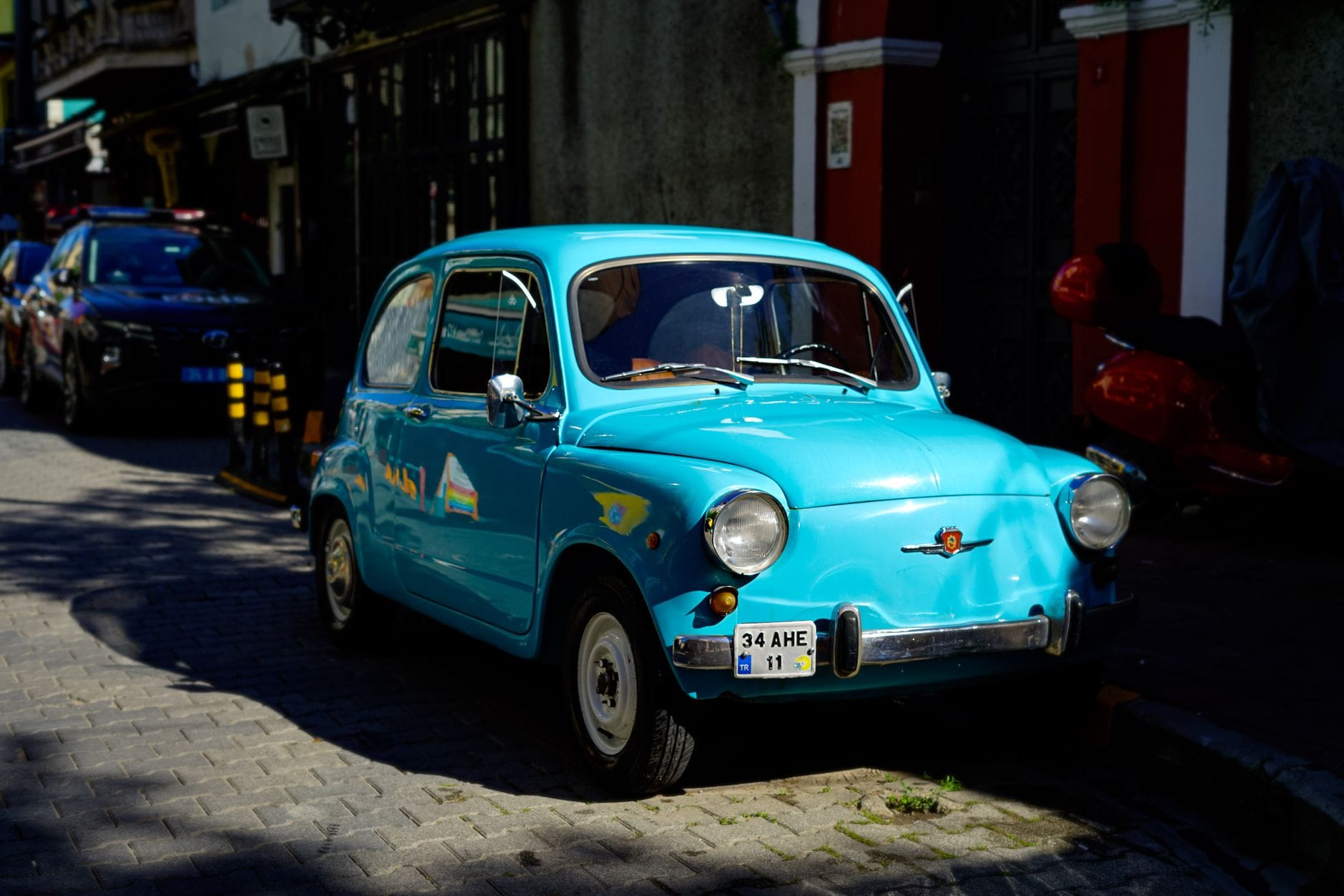 Niebieski klasyczny Fiat zaparkowany przy ulicy w słoneczny dzień