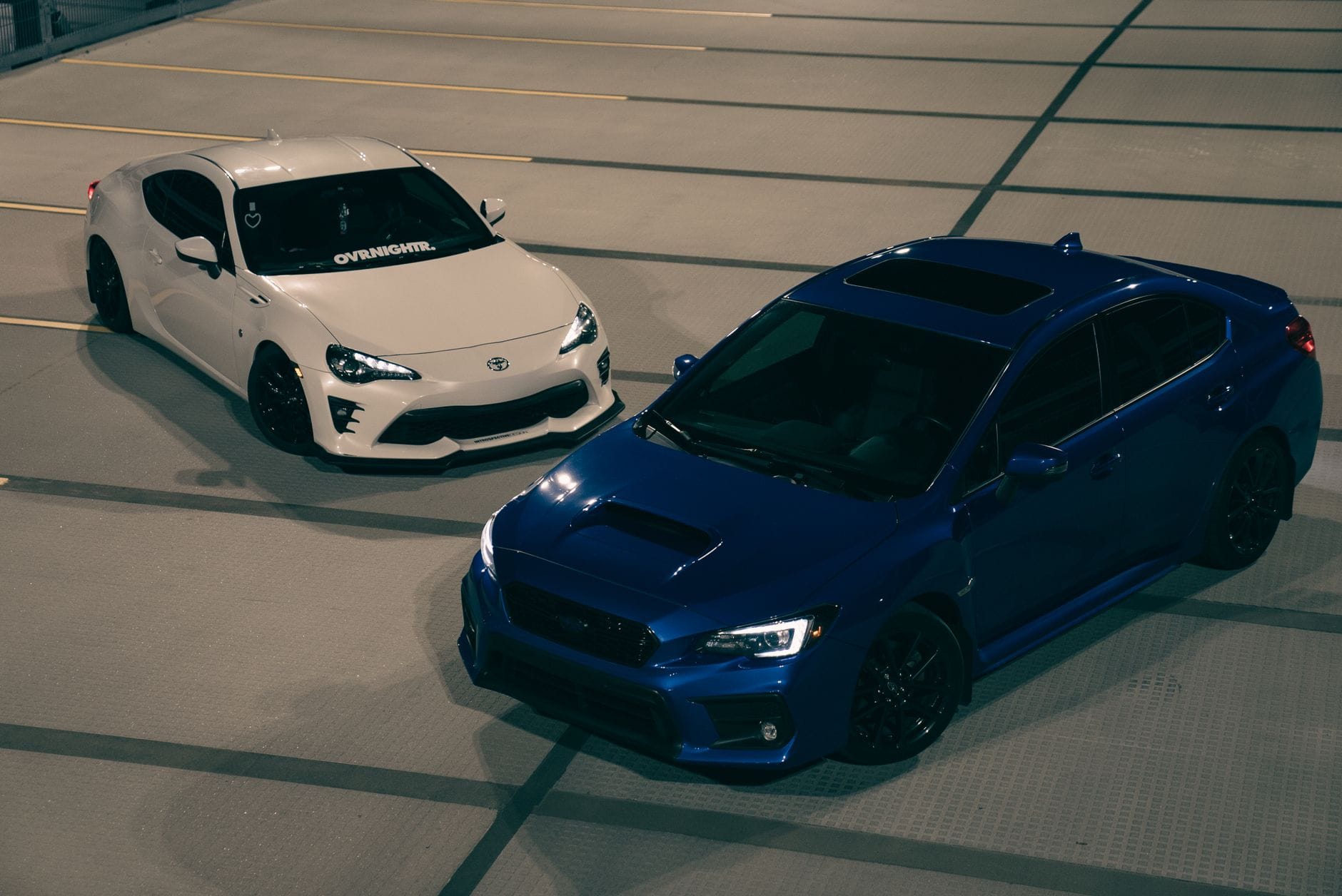 Niebieskie i białe Porsche sportowe zaparkowane nocą na pustym parkingu