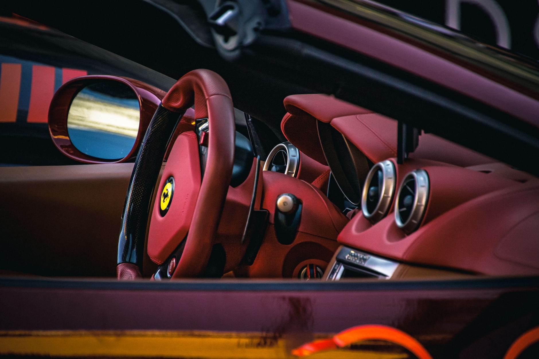 Jak działa manettino w Ferrari: tryby jazdy, kontrola trakcji i ustawienia torowe Wnętrze Ferrari z czerwonymi skórzanymi fotelami i kierownicą z manettino