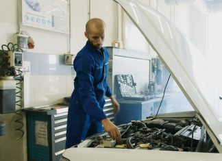 Mechanik w niebieskim kombinezonie sprawdza silnik Porsche w warsztacie